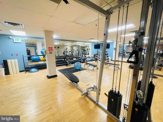 exercise room with visible vents, a paneled ceiling, and wood finished floors