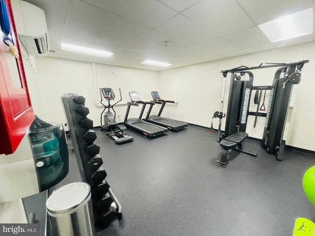 workout area with concrete block wall, a drop ceiling, and a wall mounted air conditioner