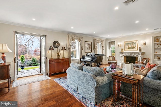 living room with a fireplace, light wood-type flooring, a healthy amount of sunlight, and ornamental molding