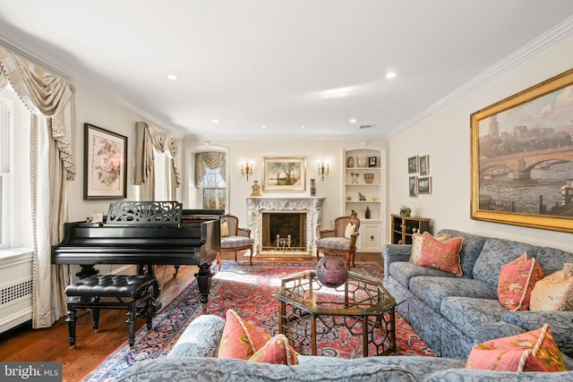 living room with hardwood / wood-style floors, built in features, a healthy amount of sunlight, a high end fireplace, and crown molding