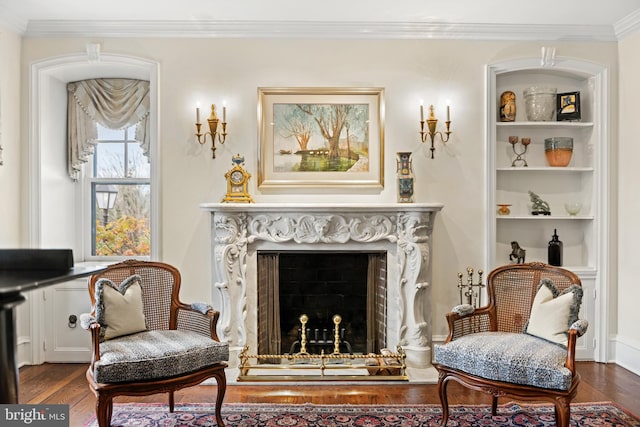 sitting room with dark wood-type flooring, built in shelves, and ornamental molding