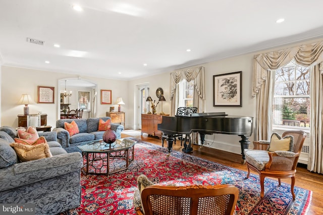 living room featuring light wood-type flooring, an inviting chandelier, and crown molding