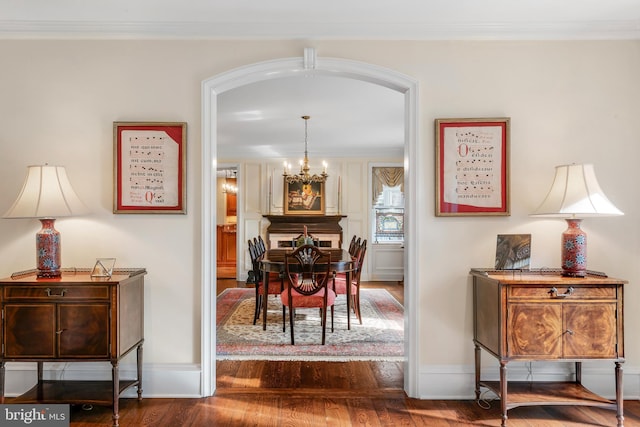 dining room featuring wood-type flooring, ornamental molding, and a notable chandelier