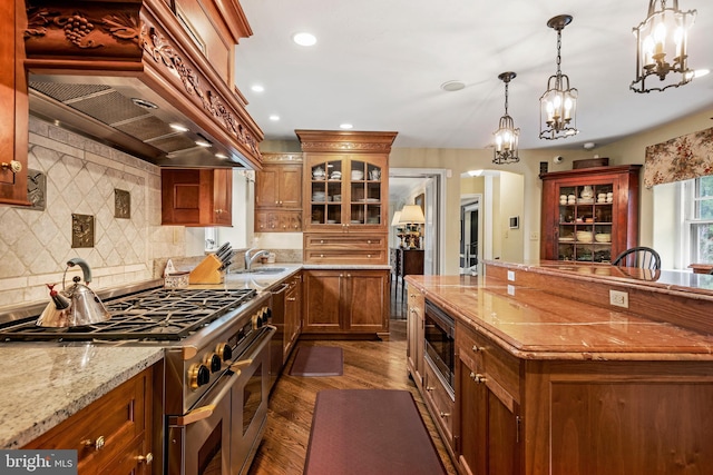 kitchen with stainless steel appliances, light stone counters, custom exhaust hood, hanging light fixtures, and dark hardwood / wood-style flooring