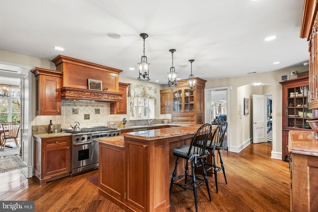 kitchen with dark hardwood / wood-style flooring, a center island, range with two ovens, and hanging light fixtures