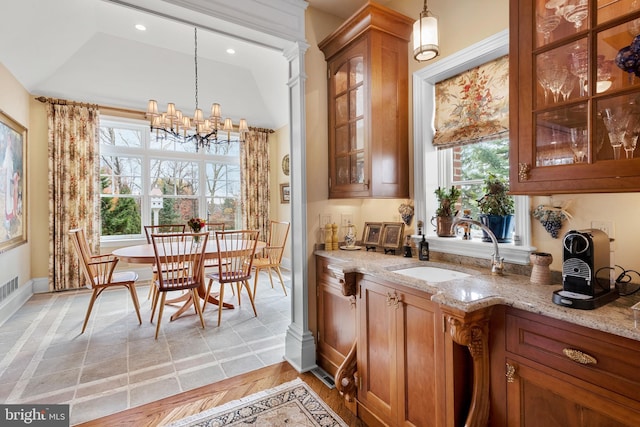 bar with light stone counters, pendant lighting, light tile patterned floors, an inviting chandelier, and sink