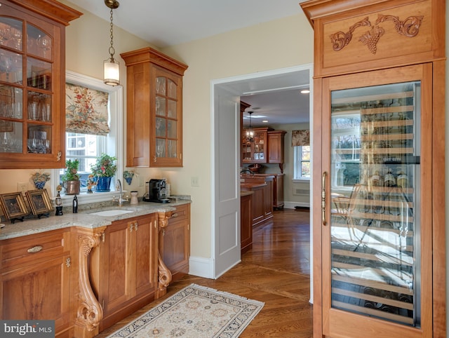 bar featuring sink, dark hardwood / wood-style floors, hanging light fixtures, and light stone countertops