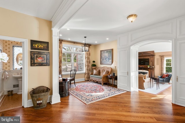 living area featuring plenty of natural light, hardwood / wood-style flooring, and ornate columns