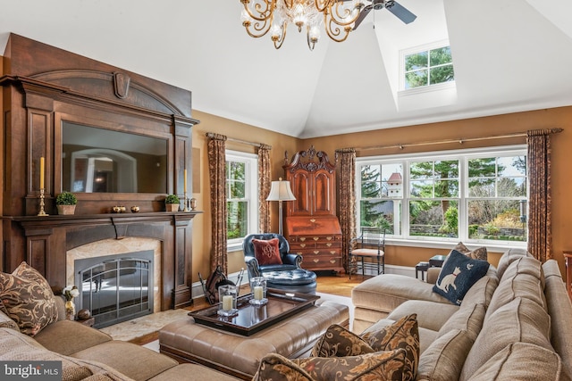 living room featuring a high end fireplace, hardwood / wood-style flooring, ceiling fan with notable chandelier, and vaulted ceiling