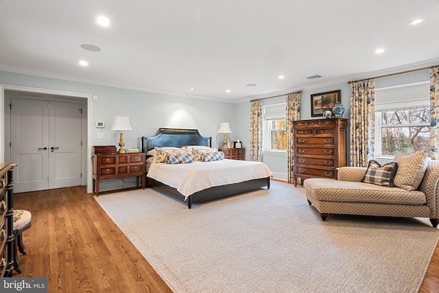 bedroom featuring wood-type flooring, multiple windows, and ornamental molding