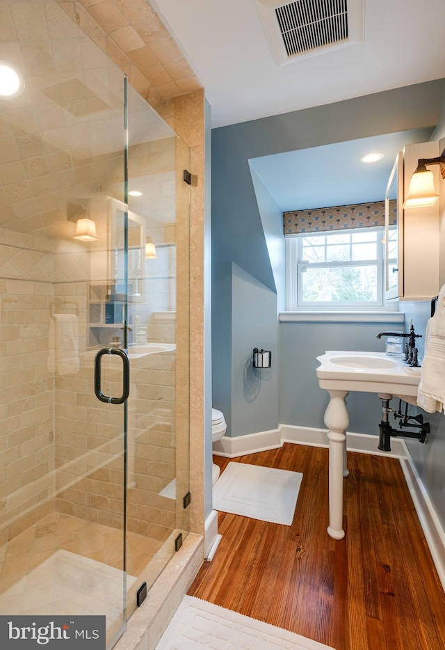 bathroom with toilet, hardwood / wood-style flooring, and walk in shower