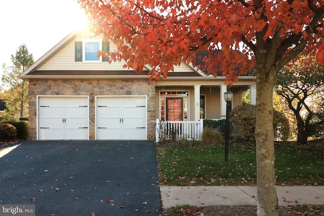 view of front of house with a garage, covered porch, and a front yard