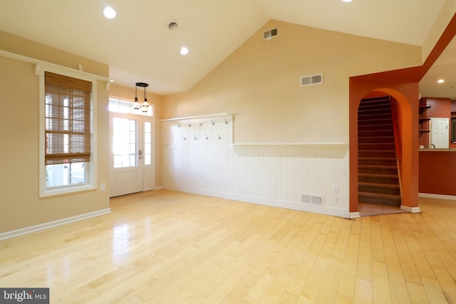 unfurnished room featuring french doors, high vaulted ceiling, light hardwood / wood-style flooring, and a notable chandelier