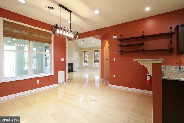 dining space featuring a wealth of natural light, light hardwood / wood-style flooring, vaulted ceiling, and sink