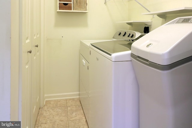 clothes washing area featuring light tile patterned floors and washer and dryer