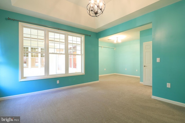 spare room featuring light carpet and a notable chandelier