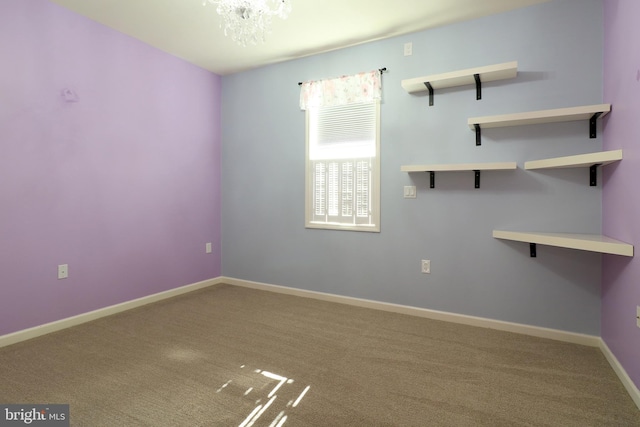 empty room featuring a chandelier and carpet floors