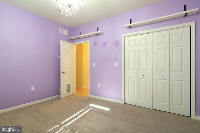 unfurnished bedroom featuring a closet, carpet, and a chandelier