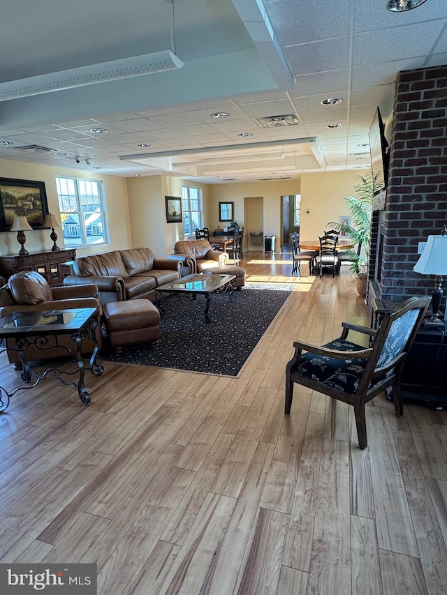 living room with a drop ceiling and wood-type flooring