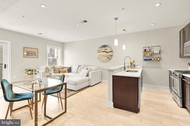 kitchen with sink, dark brown cabinets, decorative light fixtures, and stainless steel range with gas stovetop