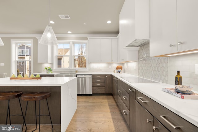 kitchen with a breakfast bar, sink, white cabinetry, dishwasher, and black electric stovetop