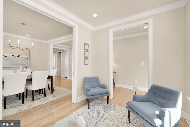 living area with hardwood / wood-style floors, an inviting chandelier, and crown molding