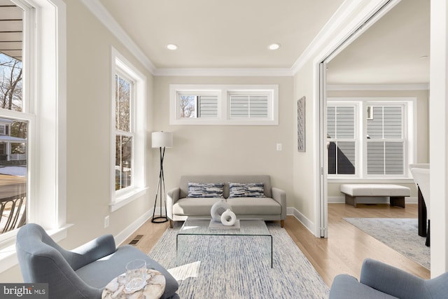 living room featuring ornamental molding, a wealth of natural light, and light hardwood / wood-style flooring