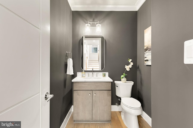 bathroom with hardwood / wood-style flooring, crown molding, vanity, and toilet