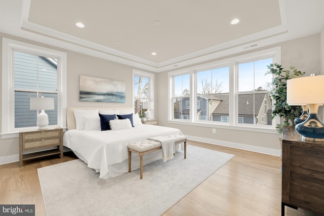 bedroom with a tray ceiling and light hardwood / wood-style flooring