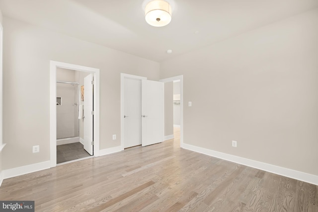 unfurnished bedroom featuring ensuite bathroom and light wood-type flooring