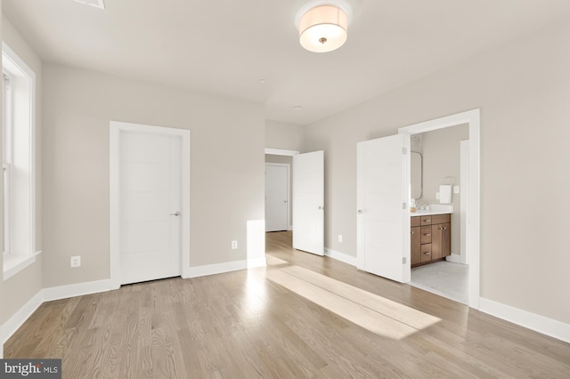 unfurnished bedroom featuring light wood-type flooring and ensuite bath