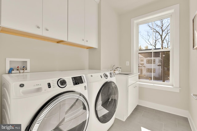 washroom with sink, independent washer and dryer, cabinets, and light tile patterned floors