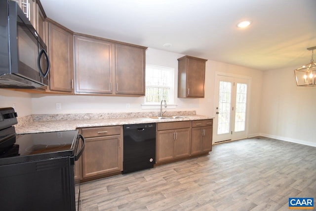 kitchen featuring an inviting chandelier, black appliances, sink, and light wood-type flooring