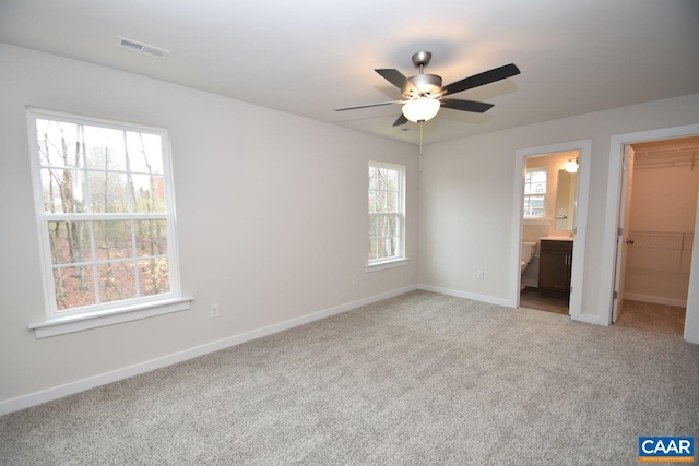 unfurnished bedroom featuring multiple windows, a walk in closet, a closet, and ceiling fan