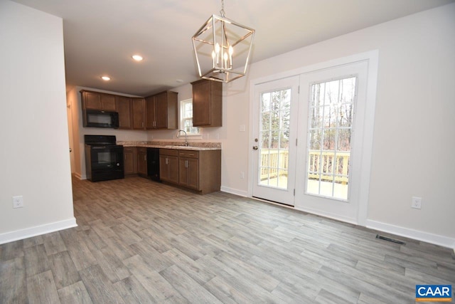 kitchen featuring light hardwood / wood-style floors, black appliances, hanging light fixtures, and sink