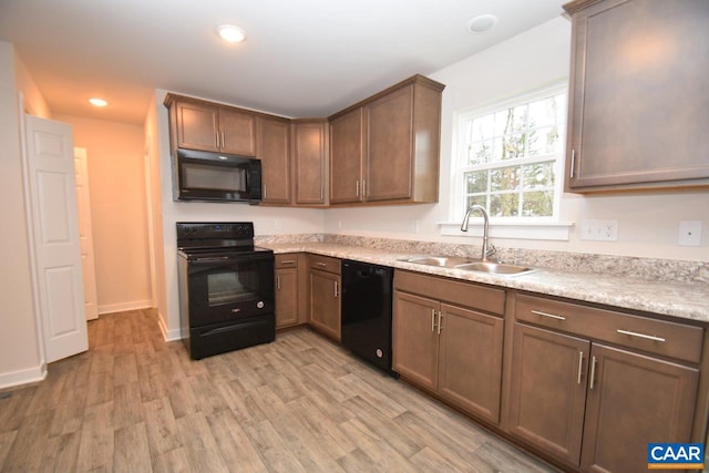 kitchen with black appliances, sink, and light wood-type flooring