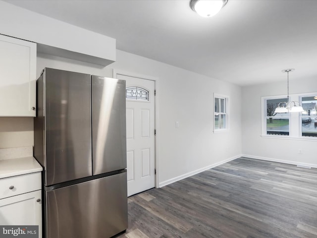 kitchen featuring pendant lighting, stainless steel fridge, dark hardwood / wood-style flooring, and white cabinetry