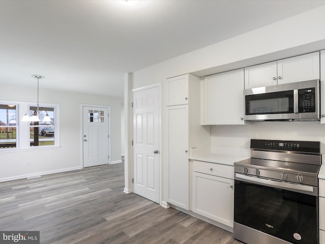 kitchen with appliances with stainless steel finishes, a notable chandelier, white cabinets, light hardwood / wood-style floors, and hanging light fixtures