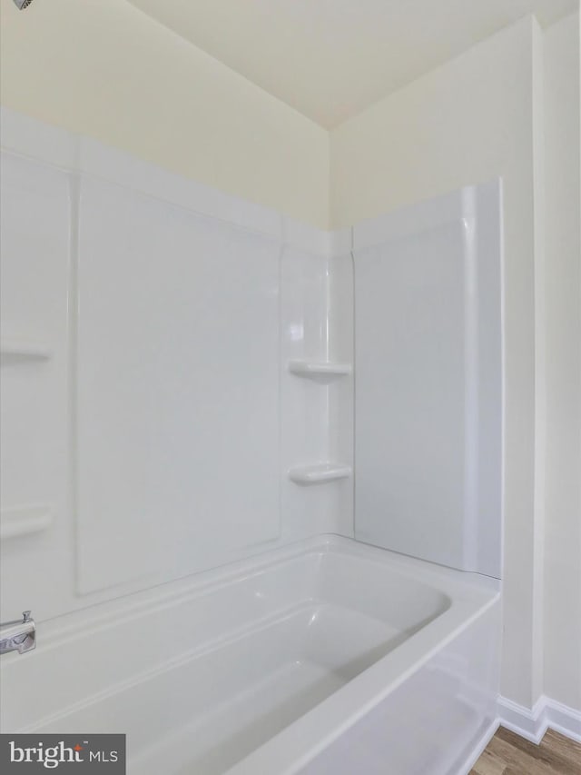 bathroom with hardwood / wood-style floors and washtub / shower combination