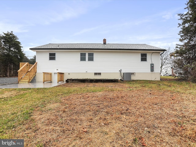 rear view of house featuring a lawn and central AC unit