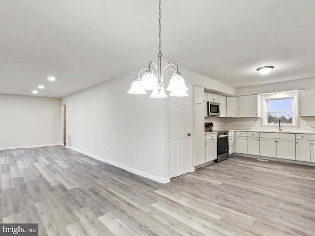 kitchen featuring white cabinets, pendant lighting, light hardwood / wood-style floors, and appliances with stainless steel finishes