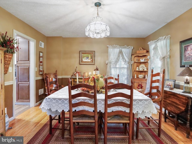 dining space with a chandelier, a textured ceiling, and light hardwood / wood-style flooring