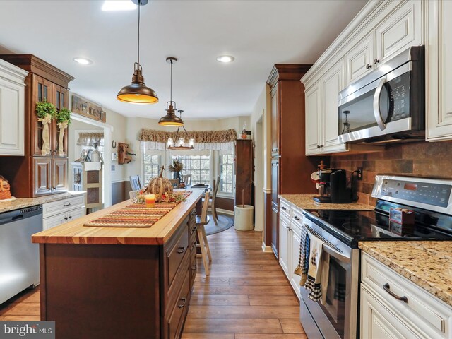 kitchen featuring a kitchen island, appliances with stainless steel finishes, dark hardwood / wood-style floors, wood counters, and hanging light fixtures