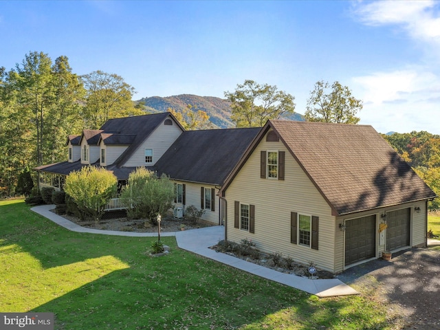 view of side of property with a lawn, a mountain view, a porch, and a garage