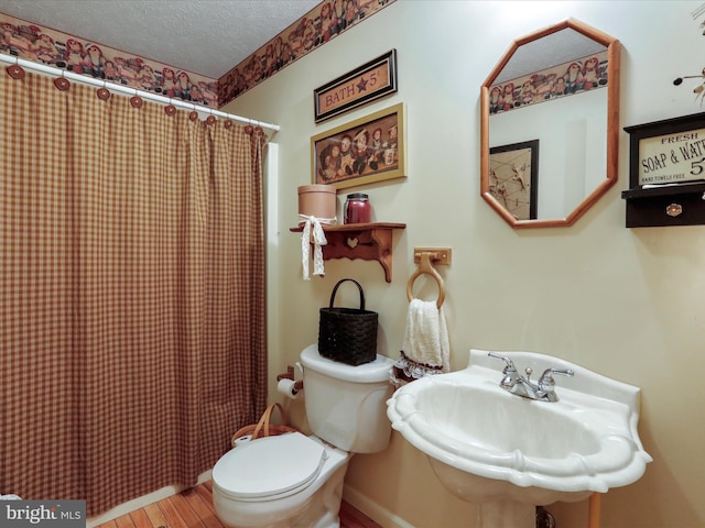 bathroom with wood-type flooring, toilet, a textured ceiling, sink, and walk in shower