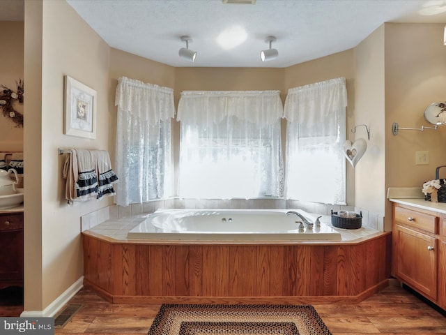 bathroom featuring a textured ceiling, vanity, hardwood / wood-style floors, and a tub