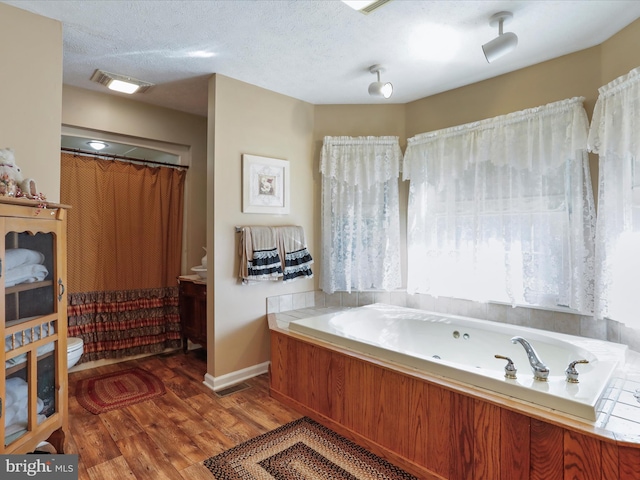 bathroom with toilet, a bathtub, a textured ceiling, and hardwood / wood-style flooring