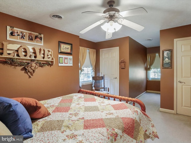 bedroom with ceiling fan, a textured ceiling, and light carpet