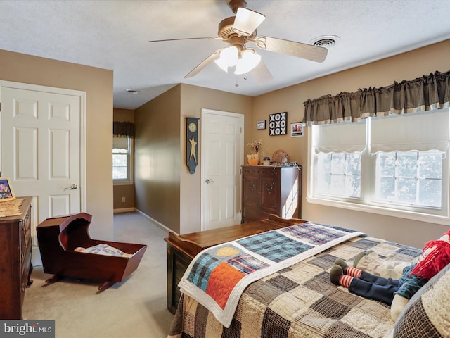 bedroom featuring ceiling fan, light colored carpet, and a textured ceiling