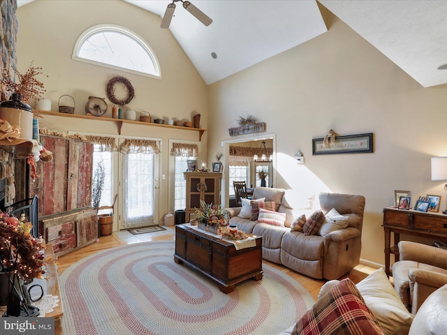 living room featuring high vaulted ceiling, ceiling fan, and light wood-type flooring